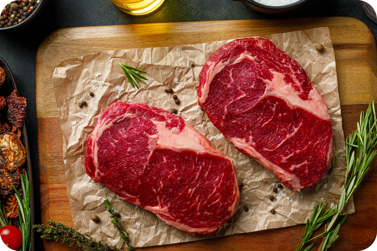 2 steaks resting ready to be cooked on a board