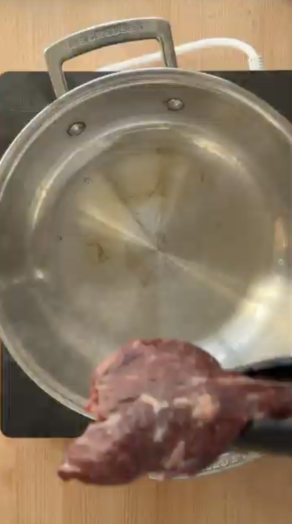Raw beef steak with tongs, ready for Le Creuset pan. Order fresh meat from Gopuff.