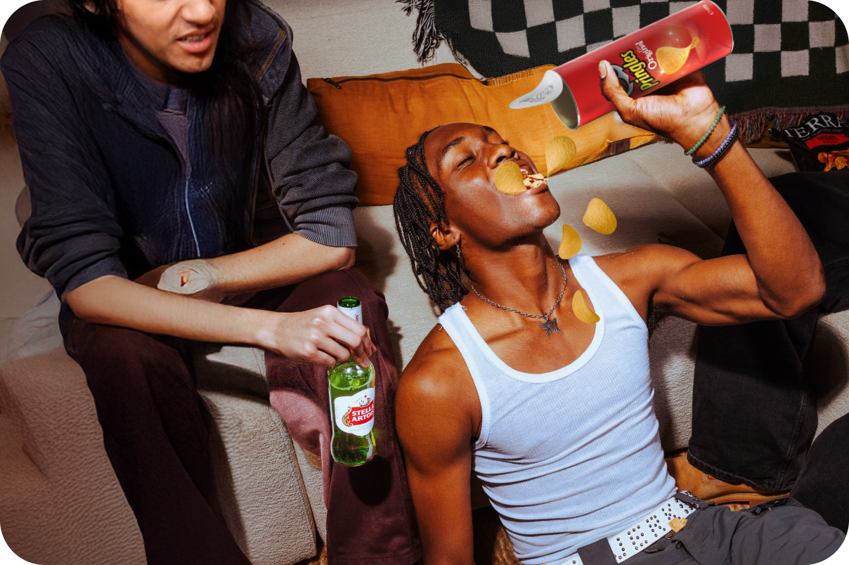 Woman sitting on an orange couch eating snacks from a bowl in a cozy living room at night.