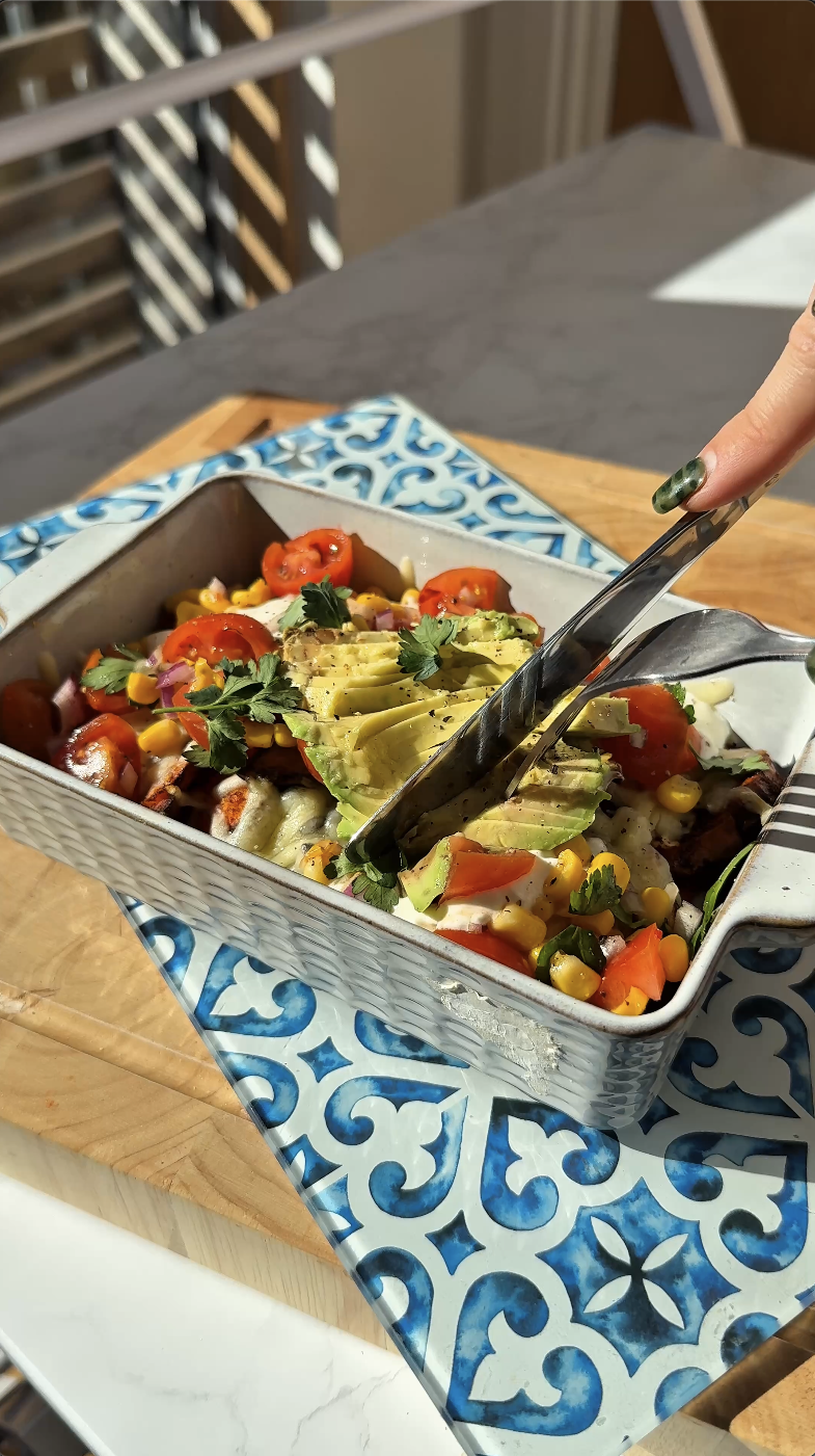 Gopuff fresh meal bowl with avocado, tomatoes, corn, and chicken, served with tongs.