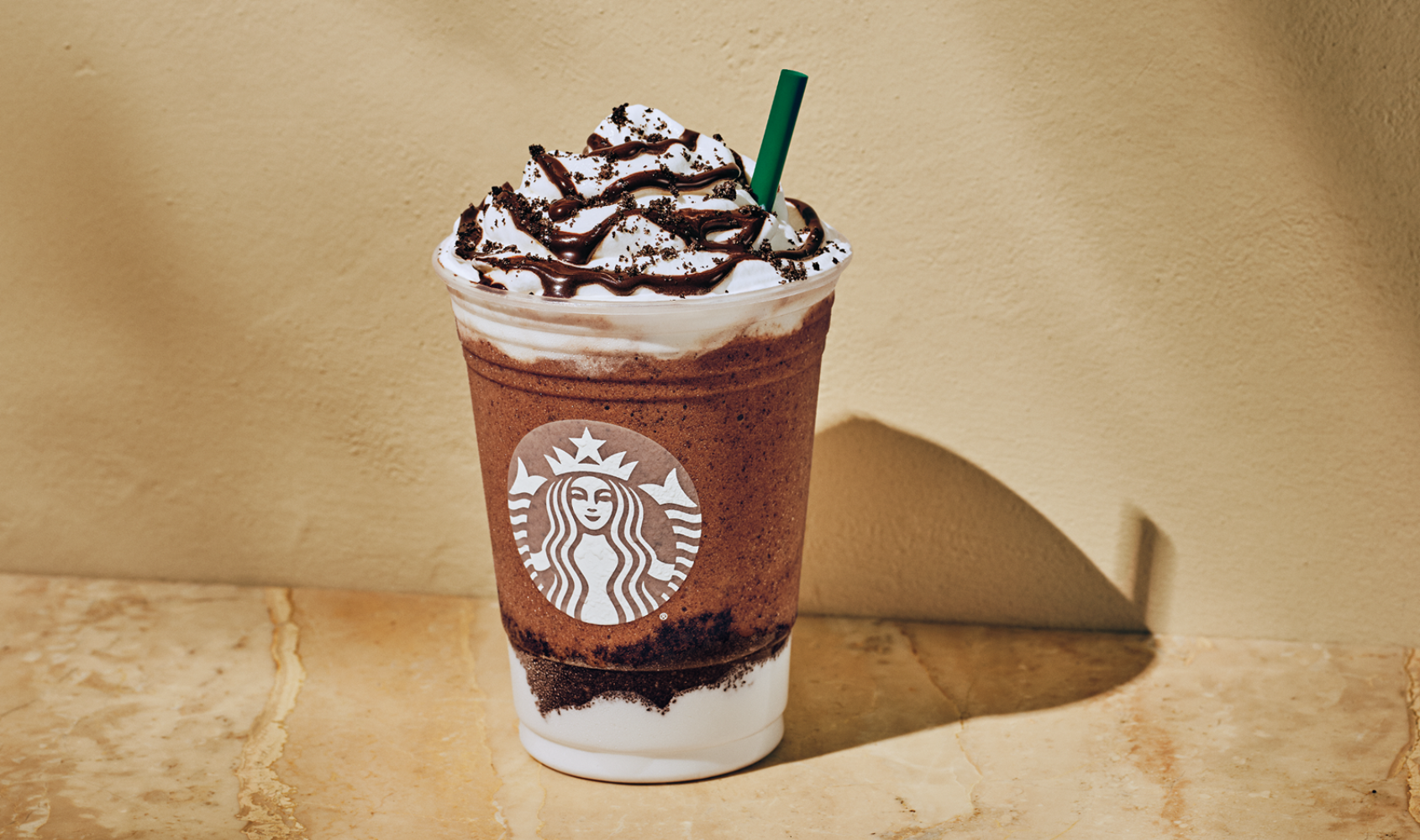 Starbucks Mocha Frappuccino with whipped cream and chocolate drizzle in a clear cup.