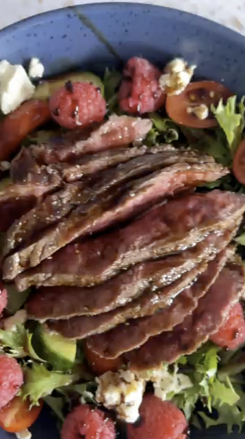 Gopuff steak salad with lettuce, tomatoes, cucumber, feta, and raspberries.