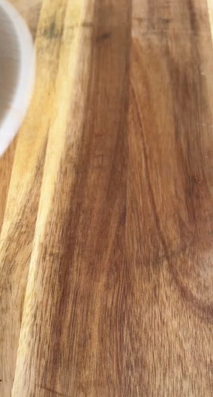 Close-up of a wooden surface with a partial white object on the left.