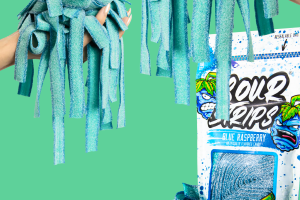 Caramelos Blue Sour Strips de frambuesa sostenidos sobre un paquete abierto sobre un fondo verde.