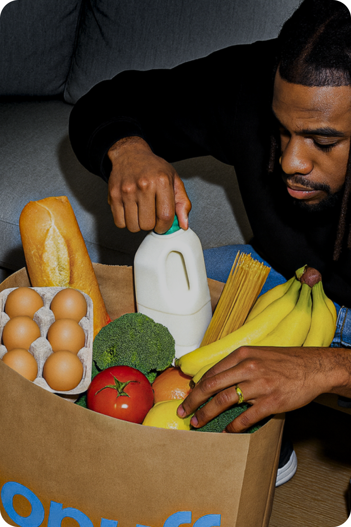 Man sitting on sofa opening his bag of groceries