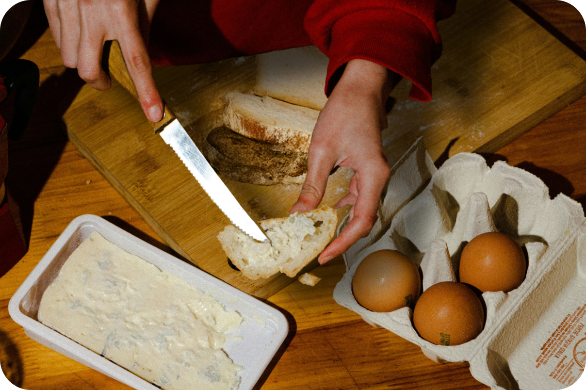 Person buttering bread next to a pack of eggs ready for breakfast